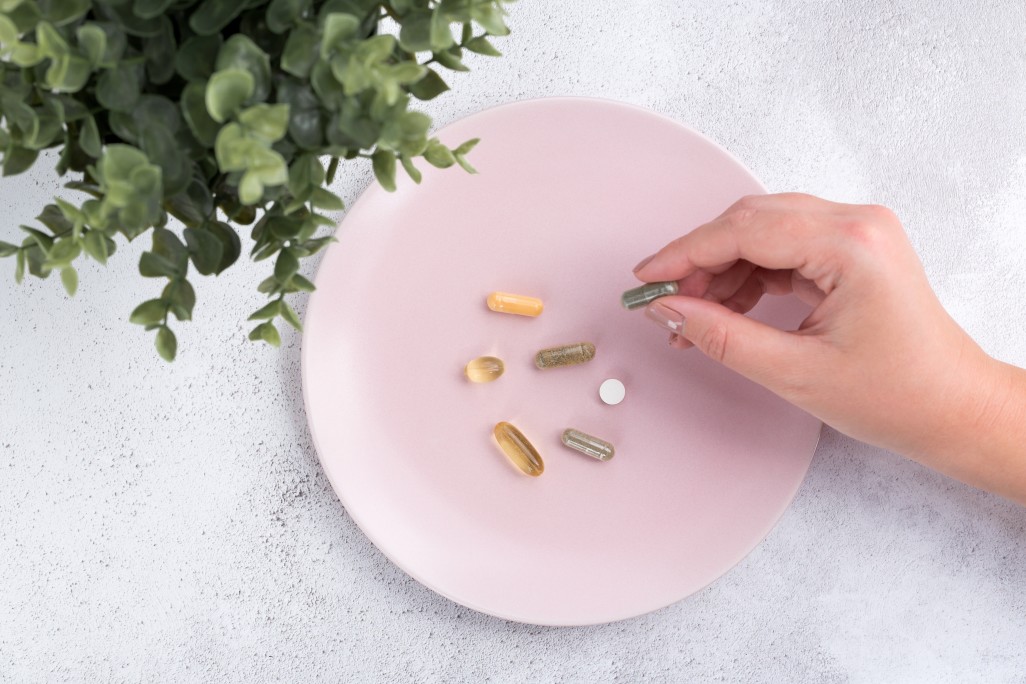 aerial-view-of-the-hand-of-a-young-woman-picking-up-a-supplement-capsule-amongst-other-pills